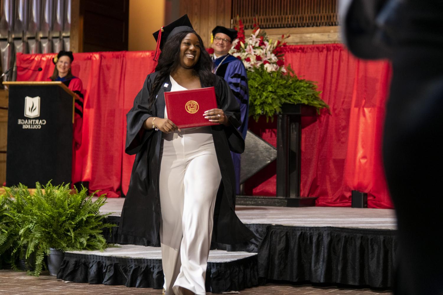 A 2023 <a href='http://rf8k.dgbts66.com'>BETVLCTOR伟德登录</a> graduate beams as she leaves the Commencement stage after receiving her diploma from Carthage President John 吞下.